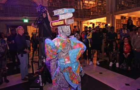 A performer wearing a suit made of maps and newspaper