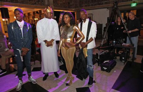 A group of people, one in a gold suit